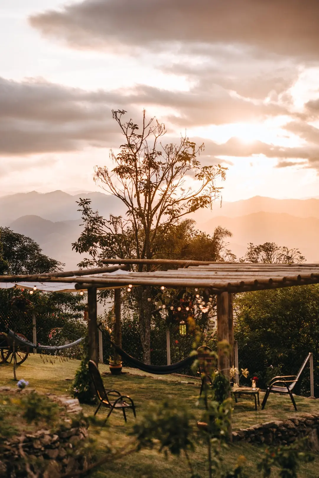 Pôr do sol sobre as montanhas da Mantiqueira visto do gramado, com o pergolado em primeiro plano