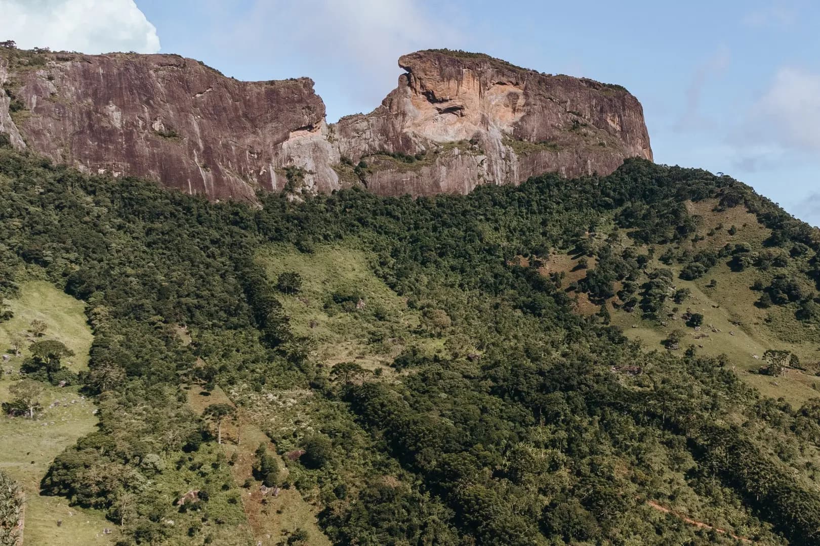 Paredão da Pedra do Baú visto da pousada, com a mata da Mantiqueira cobrindo as encostas