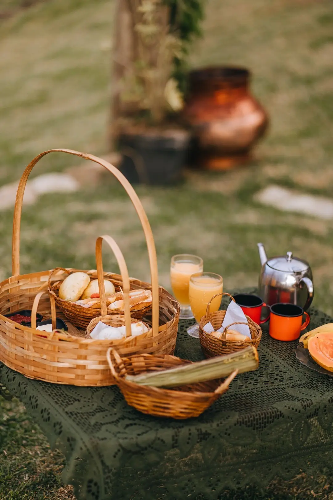 Café da manhã na mesa do jardim: cestas de pães, bolo de milho, sucos, chá e mamão