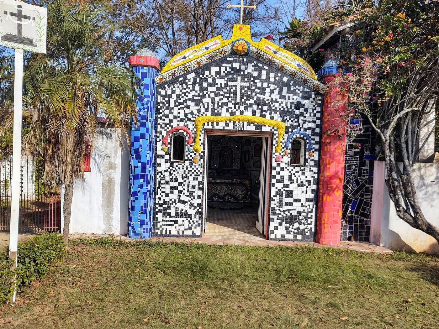 Capelinha de mosaico do Centro, revestida de caco preto e branco, com colunas coloridas e porta aberta
