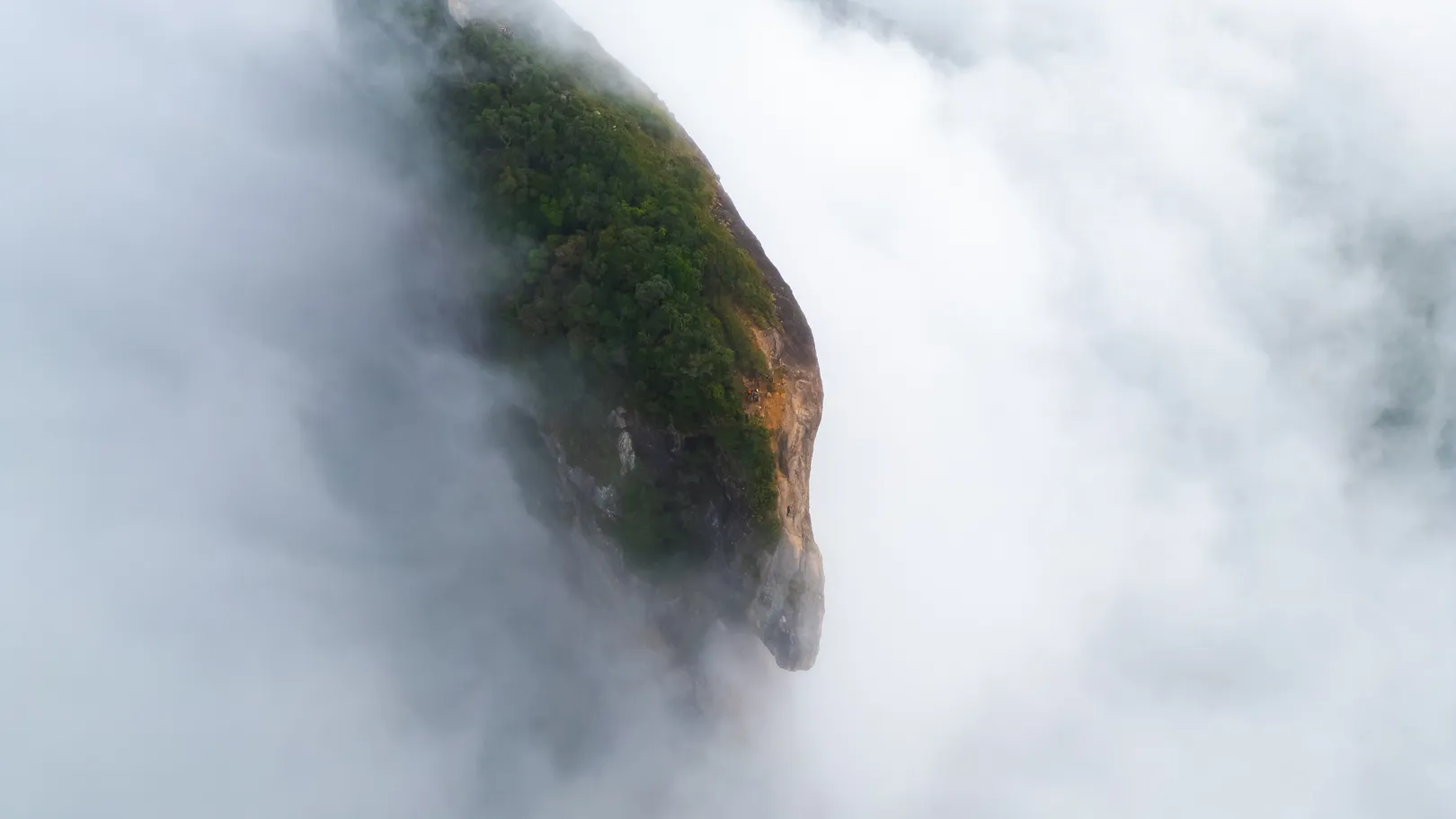 Ponta do paredão da Pedra do Baú aparecendo por entre as nuvens