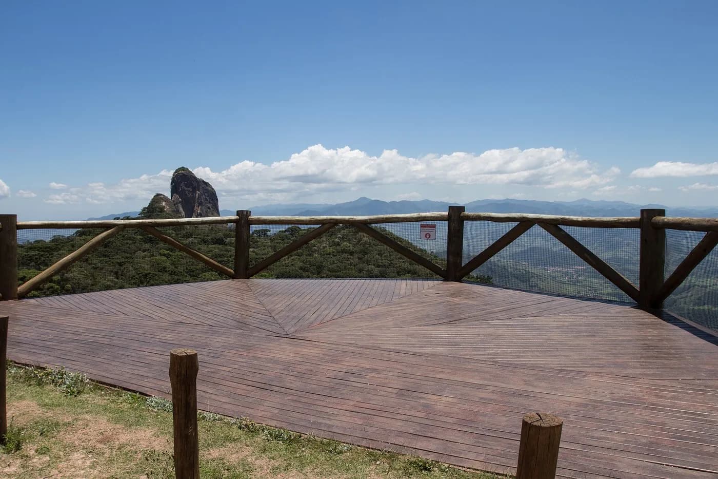 Deck de madeira da rampa de voo livre, com corrimão de tronco e a Pedra do Baú no horizonte